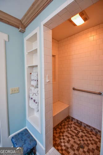 bathroom with crown molding, a tile shower, and tile patterned floors