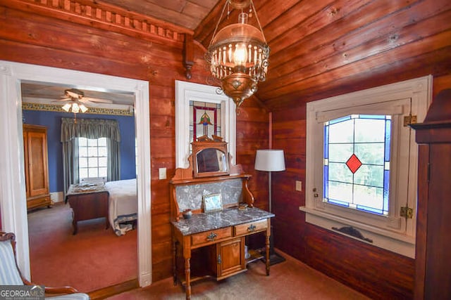 interior space featuring lofted ceiling, wooden walls, carpet, wooden ceiling, and ceiling fan with notable chandelier