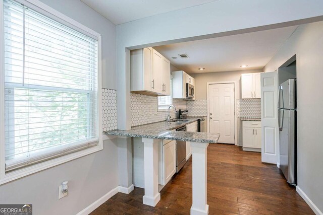 2836 Harlan Dr, Atlanta, GA 30344 - kitchen featuring light stone countertops, a peninsula, white cabinets, and stainless steel appliances