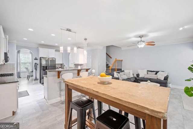 dining space with ornamental molding, sink, and ceiling fan