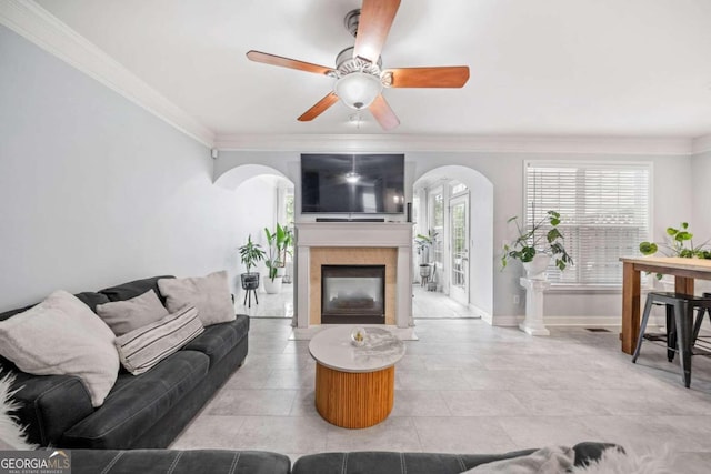 living room with ceiling fan, a fireplace, and crown molding