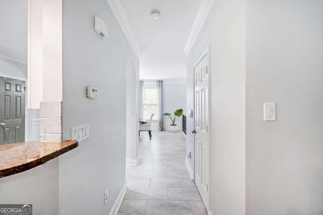 hallway featuring ornamental molding and light tile patterned flooring