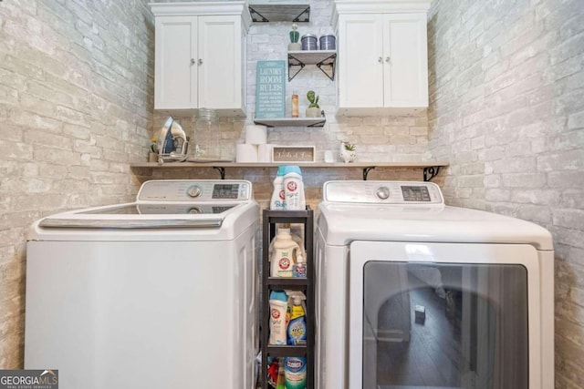 washroom featuring cabinets, independent washer and dryer, and brick wall