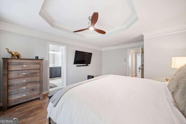 bedroom with ceiling fan, a raised ceiling, connected bathroom, ornamental molding, and dark wood-type flooring