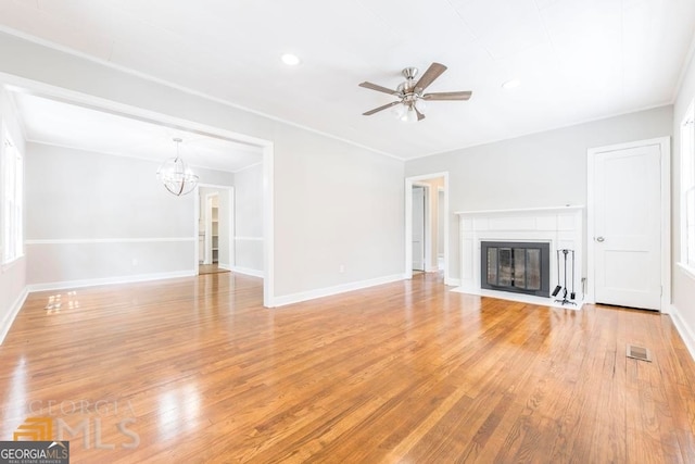 unfurnished living room featuring ceiling fan with notable chandelier, light hardwood / wood-style floors, and ornamental molding