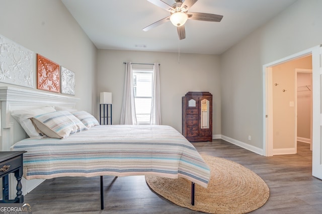 bedroom featuring ceiling fan, hardwood / wood-style floors, and a walk in closet