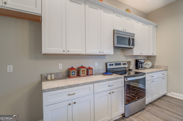 kitchen featuring appliances with stainless steel finishes, light hardwood / wood-style floors, light stone counters, and white cabinets