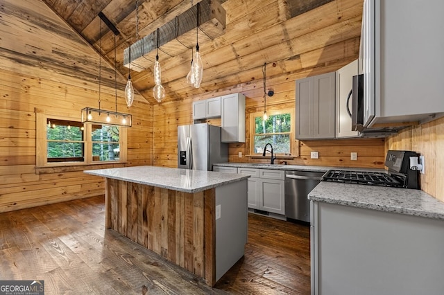 kitchen featuring pendant lighting, vaulted ceiling with beams, appliances with stainless steel finishes, and a center island