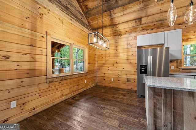 kitchen featuring a wealth of natural light, light stone countertops, stainless steel fridge with ice dispenser, and decorative light fixtures