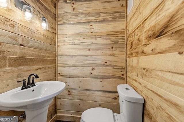 bathroom with sink, wooden walls, and toilet