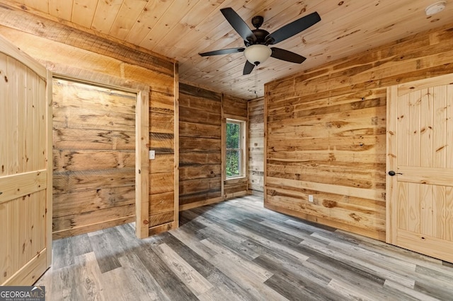 spare room with wood ceiling, wooden walls, ceiling fan, and wood-type flooring