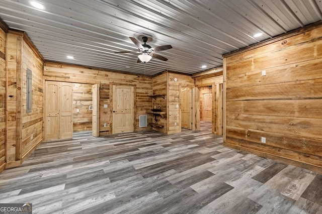 unfurnished living room with wood walls, ceiling fan, wooden ceiling, and dark wood-type flooring