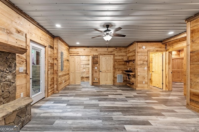 interior space featuring wood walls, hardwood / wood-style floors, and ceiling fan