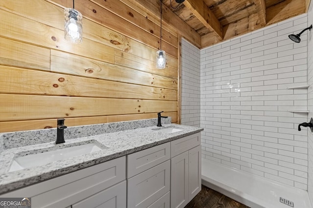 bathroom with vanity, wooden walls, hardwood / wood-style floors, and a tile shower