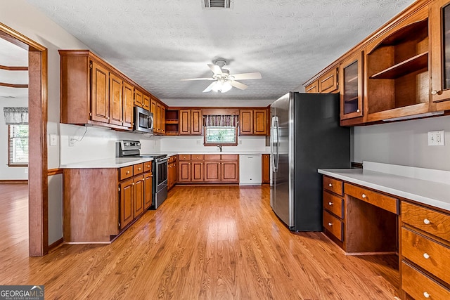 kitchen featuring a textured ceiling, sink, light hardwood / wood-style flooring, appliances with stainless steel finishes, and ceiling fan