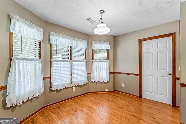 unfurnished room featuring light wood-type flooring and a textured ceiling