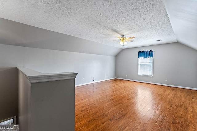 additional living space featuring ceiling fan, a textured ceiling, lofted ceiling, and hardwood / wood-style floors