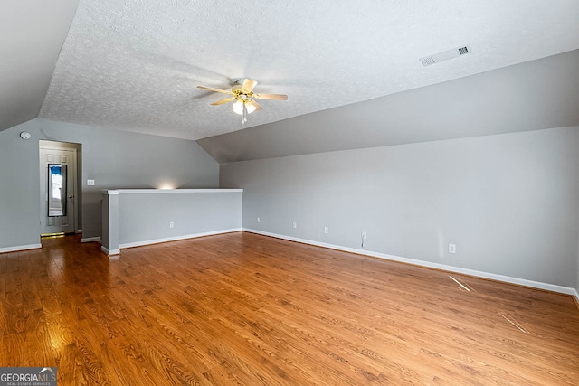 bonus room with lofted ceiling, ceiling fan, hardwood / wood-style floors, and a textured ceiling