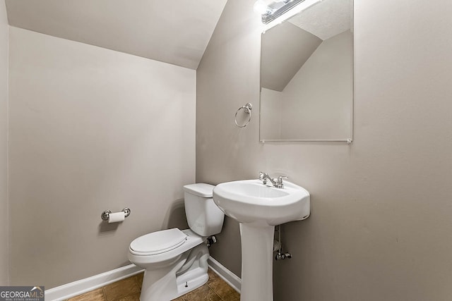 bathroom with vaulted ceiling, toilet, and tile patterned floors