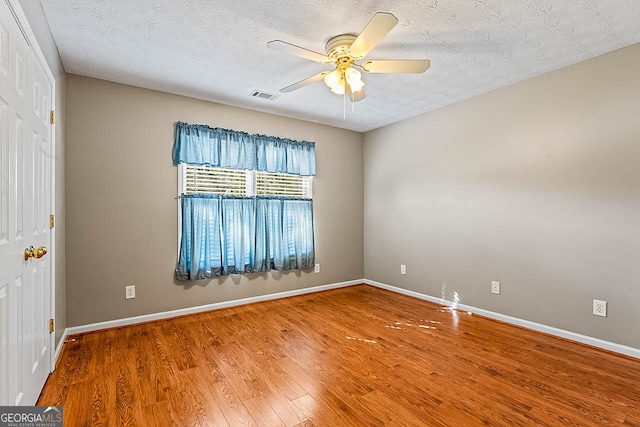 unfurnished room featuring ceiling fan, hardwood / wood-style floors, and a textured ceiling