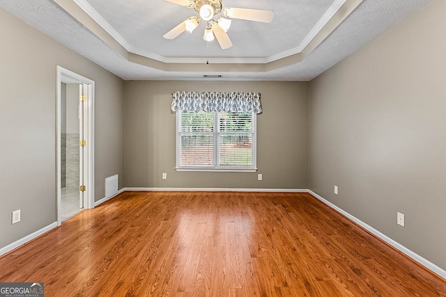 spare room with ceiling fan, a tray ceiling, hardwood / wood-style floors, and ornamental molding