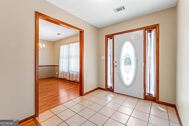 entryway with light wood-type flooring and a notable chandelier