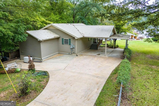 rear view of house featuring a lawn and a carport