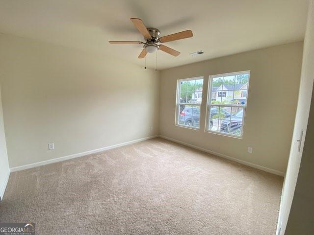 spare room with ceiling fan and light colored carpet