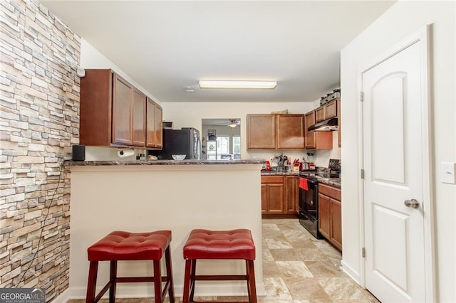 kitchen with kitchen peninsula, stainless steel refrigerator, a kitchen breakfast bar, ceiling fan, and black / electric stove