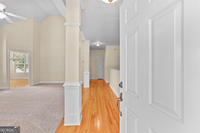 corridor with light wood-type flooring, ornate columns, and lofted ceiling