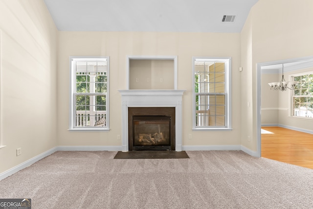 unfurnished living room featuring carpet and a chandelier