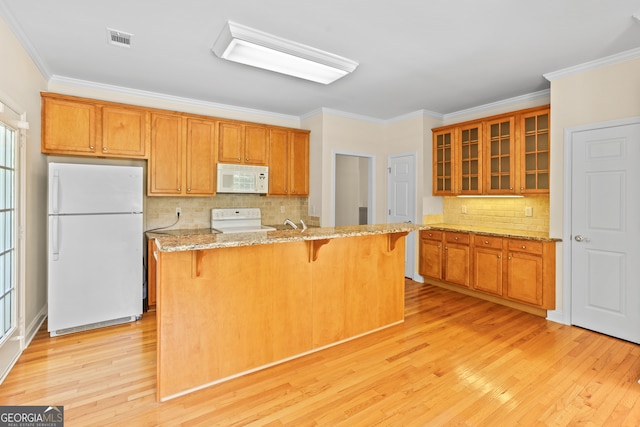 kitchen featuring light hardwood / wood-style floors, white appliances, ornamental molding, and a kitchen bar