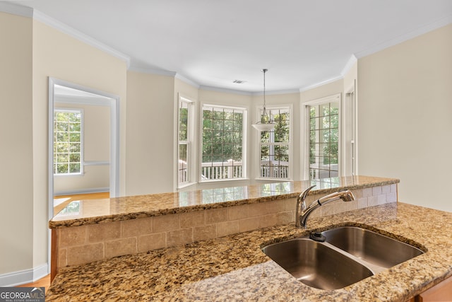 kitchen featuring light stone countertops, crown molding, decorative light fixtures, hardwood / wood-style floors, and sink