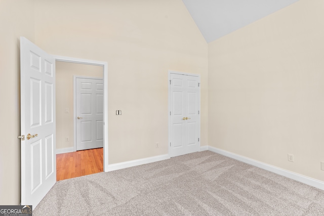 unfurnished bedroom with light carpet and lofted ceiling