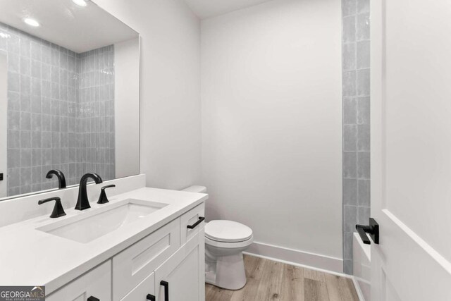 bathroom with wood-type flooring, vanity, and toilet