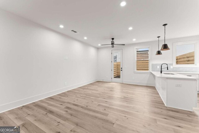 unfurnished living room featuring ceiling fan, light hardwood / wood-style flooring, and sink