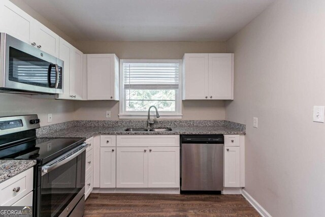 kitchen with appliances with stainless steel finishes, white cabinets, dark hardwood / wood-style flooring, stone countertops, and sink