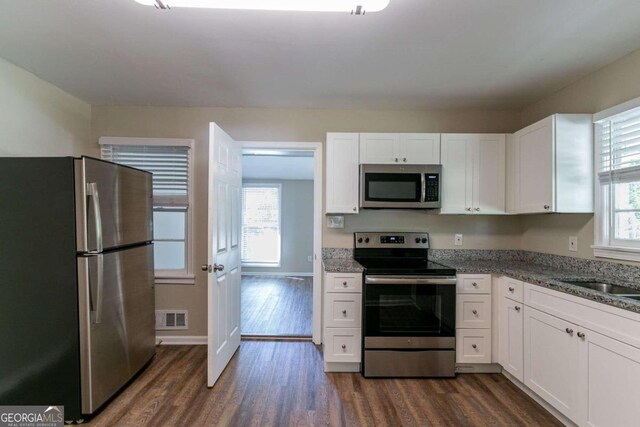 kitchen featuring stainless steel appliances, dark hardwood / wood-style floors, a healthy amount of sunlight, and white cabinetry