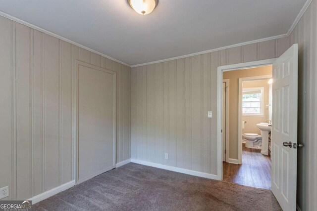 unfurnished bedroom featuring ornamental molding and dark carpet