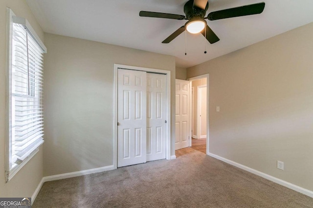 unfurnished bedroom featuring ceiling fan, light colored carpet, and a closet