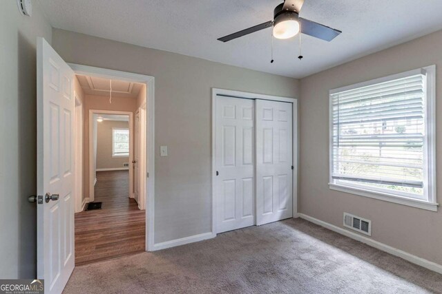 unfurnished bedroom featuring a closet, multiple windows, hardwood / wood-style flooring, and ceiling fan