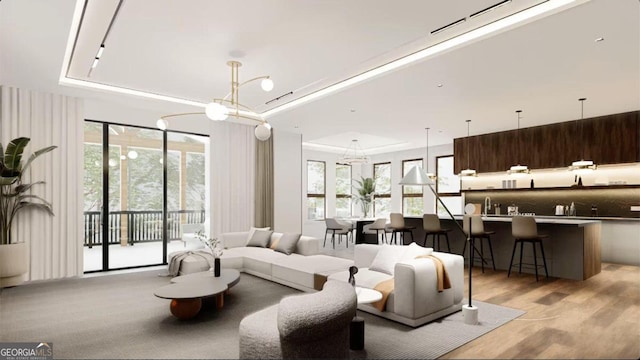 living room featuring light wood-type flooring, a tray ceiling, and sink