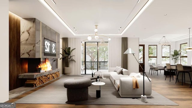 living room featuring light wood-type flooring, a raised ceiling, and a chandelier