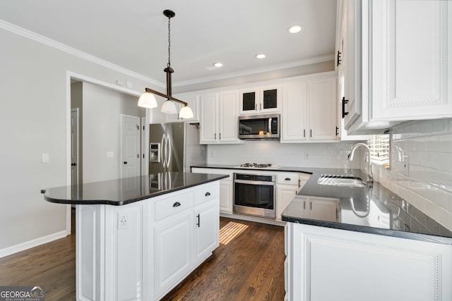 kitchen with a center island, sink, white cabinetry, stainless steel appliances, and decorative light fixtures