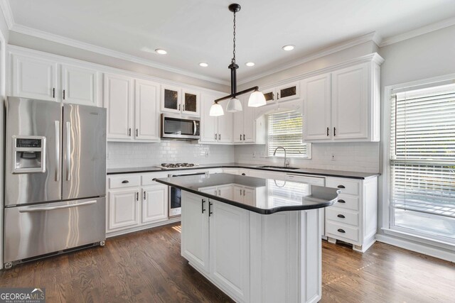 kitchen with appliances with stainless steel finishes, pendant lighting, and white cabinets