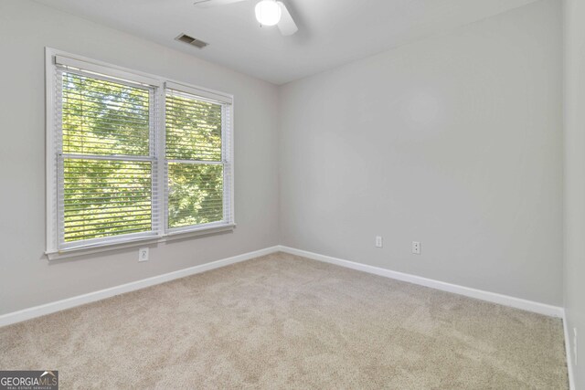 carpeted empty room with ceiling fan and a healthy amount of sunlight