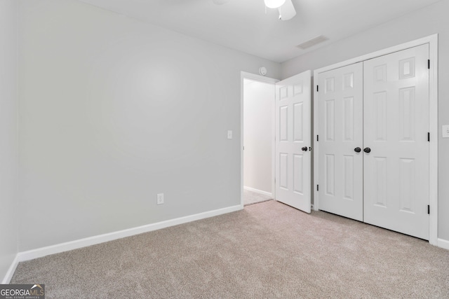 unfurnished bedroom featuring ceiling fan, a closet, and light carpet