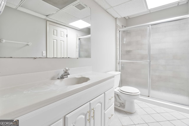 bathroom with an enclosed shower, a drop ceiling, tile patterned floors, vanity, and toilet