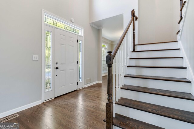 entrance foyer featuring crown molding and dark wood-type flooring