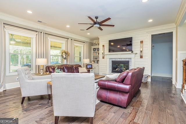 living room with ceiling fan, a fireplace, crown molding, and hardwood / wood-style floors